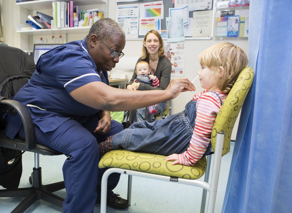 Practice Nurse delivering child vaccination to a young girl.