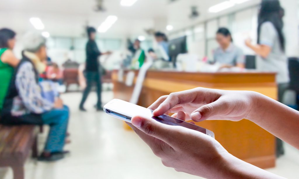 A nurse using a mobile phone in a large GP Practice reception.