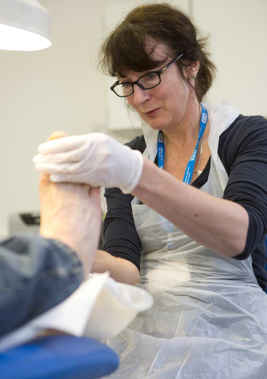 A nurse tends to the foot of a homeless man