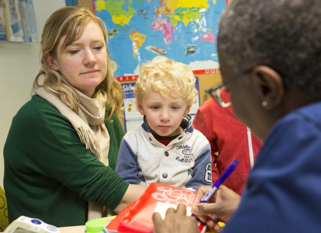 A mother and young blond boy visits the Practice Nurse