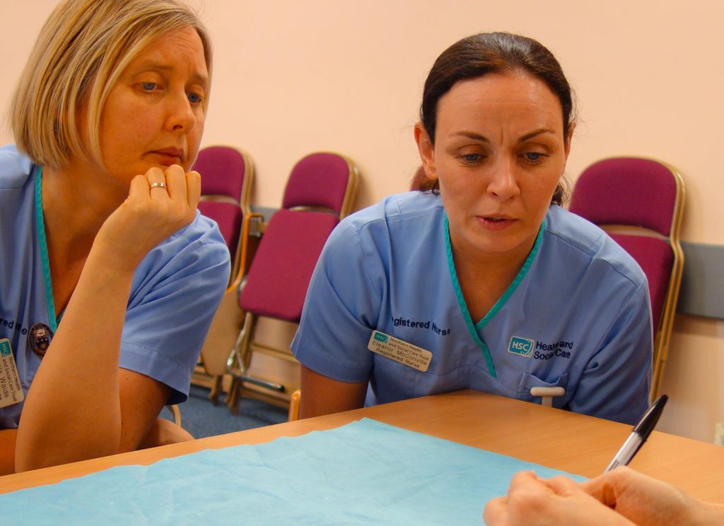 A group of nurses in pale blue uniforms in a training session