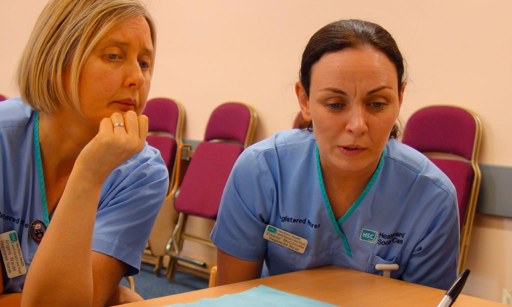 A group of nurses in pale blue uniforms in a training session