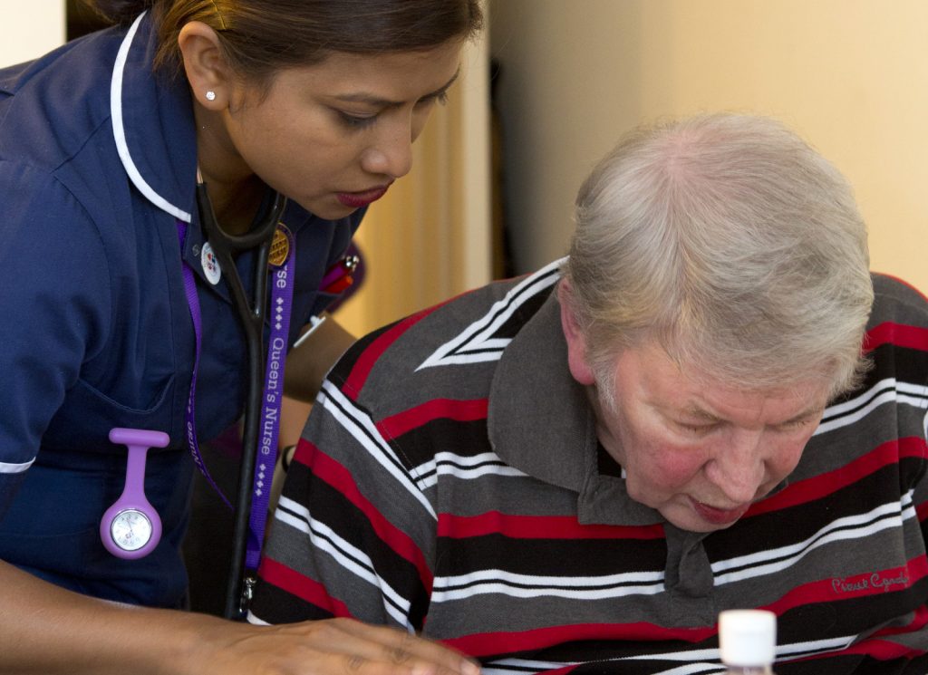 Nurse leans over an elderly patient