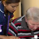 Nurse leans over an elderly patient