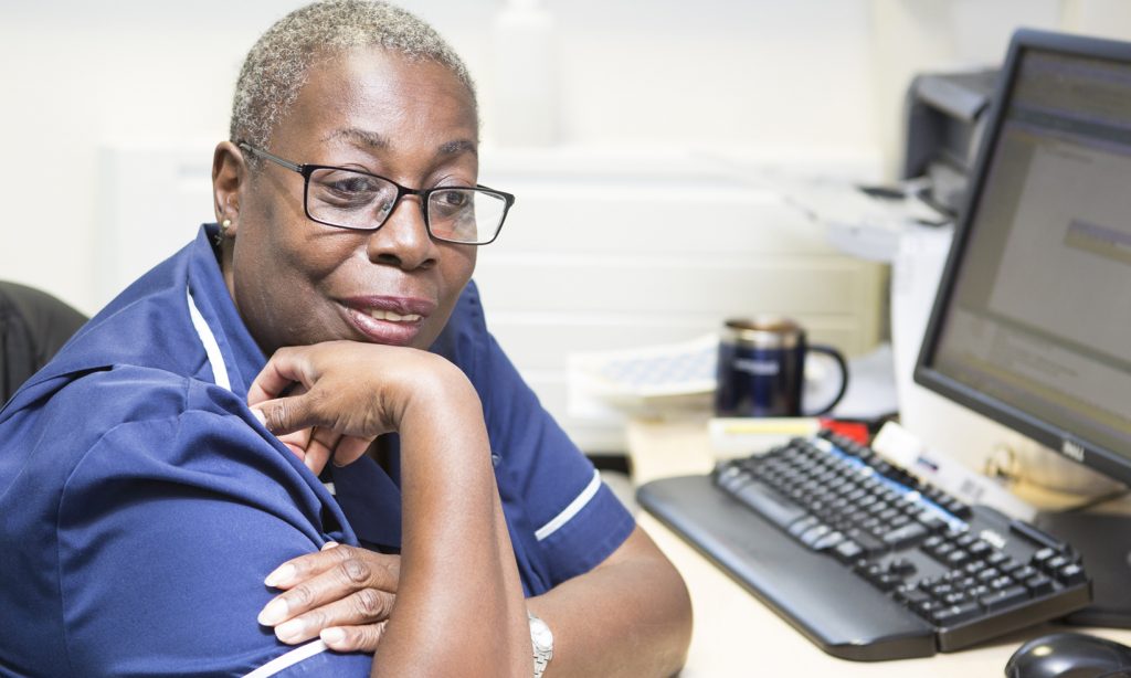 Practice nurse with patient at computer