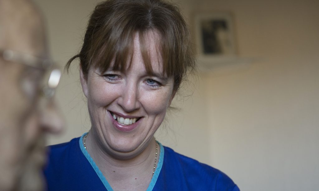 District Nurse with elderly patient smiling and chatting