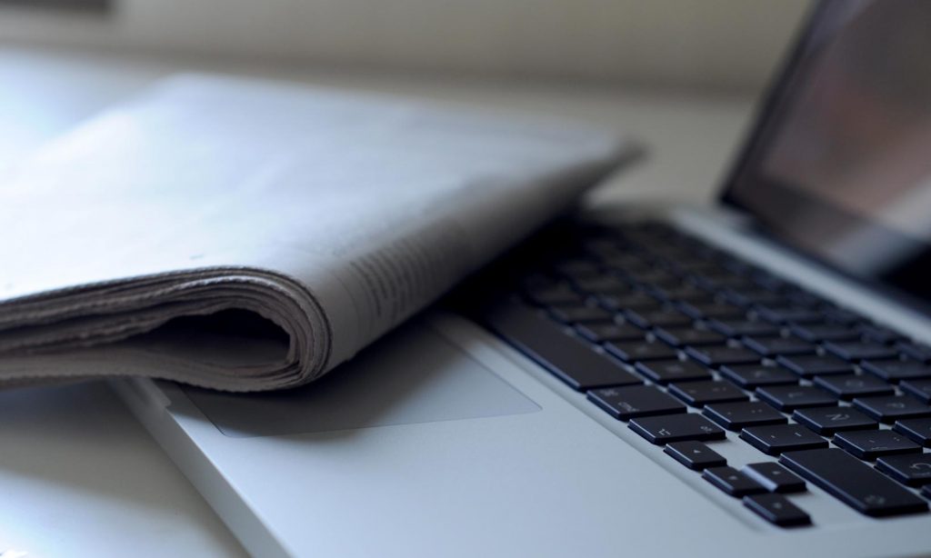 A newspaper lying over the keyboard of a laptop