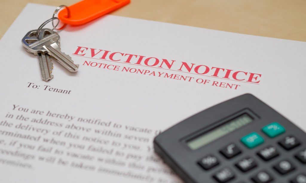 an eviction notice on a table with a calculator and set of keys