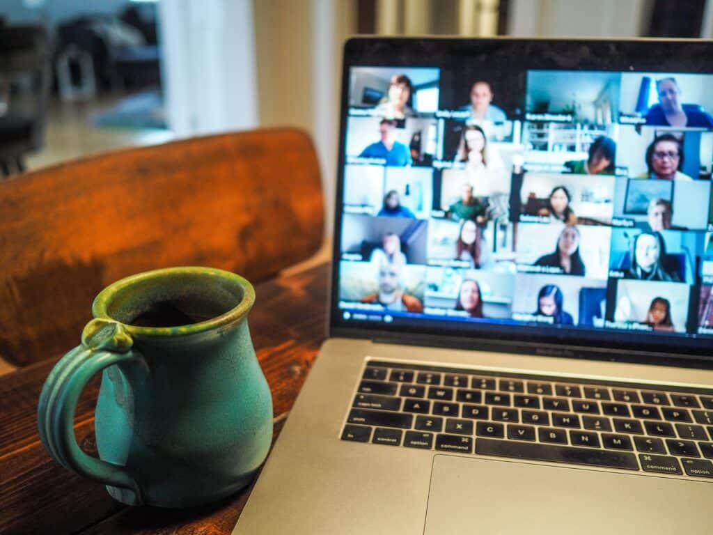 Online video conference on laptop screen and a cup